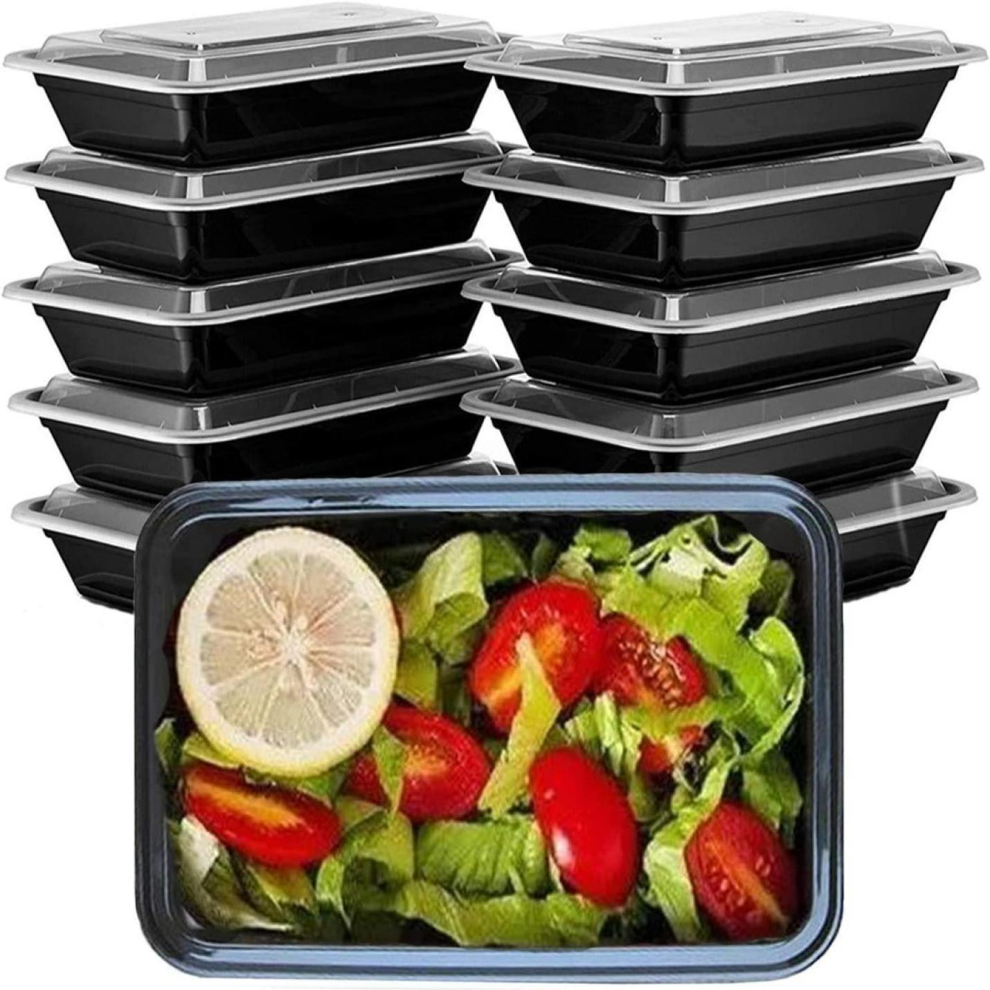 Bespaar tijd en geld met onze hoogwaardige meal prep bakjes met een stapel zwarte herbruikbare plastic maaltijdvoorbereidingscontainers met een transparante deksel, waarvan er één een salade toont met sla, tomaten en een plakje citroen.