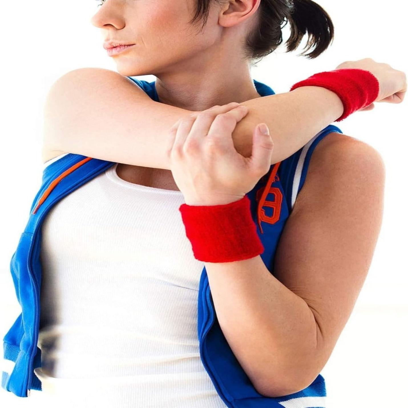 Een vrouw die haar arm strekt, gekleed in een witte tanktop, blauw sportvest en zweetbandjes voor basketbal, voetbal en atletiek - Verbeter je sportieve prestaties!