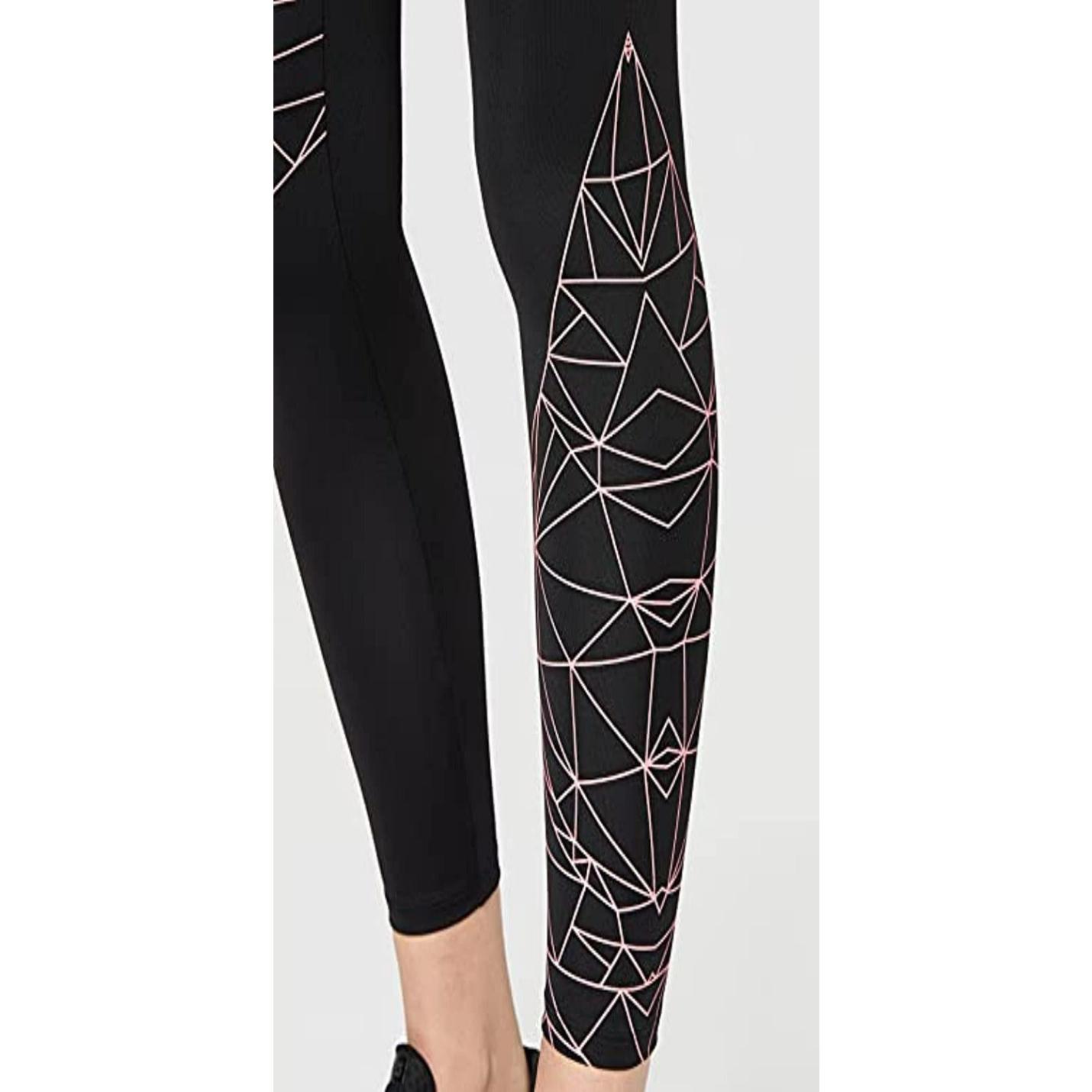 Close-up van de benen van een vrouw in het zwart Ervaar comfort en stijl met onze sportlegging voor dames met een geometrisch wit en roze lijnontwerp op één been.