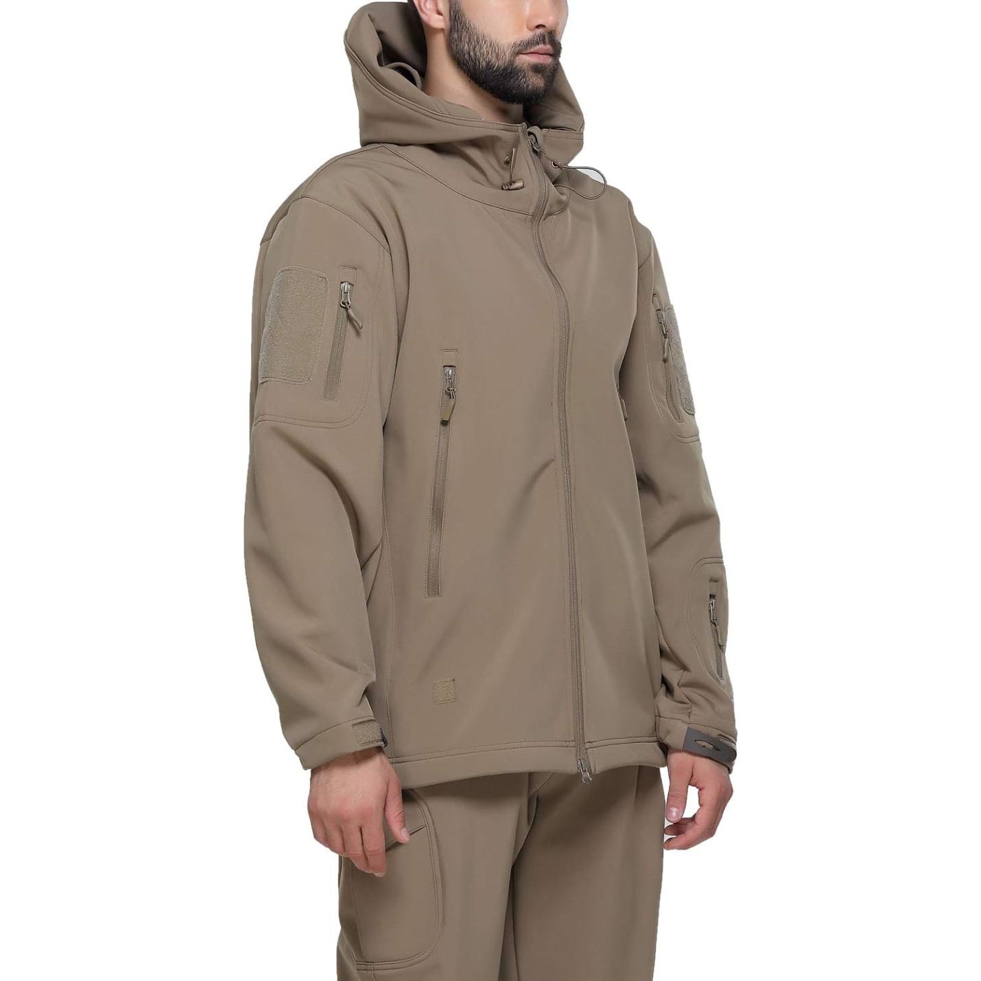 Man in een camouflage tactische heren softshell jas met meerdere zakken met ritssluiting en klittenbandpatches, staande met handen gedeeltelijk in broekzakken.