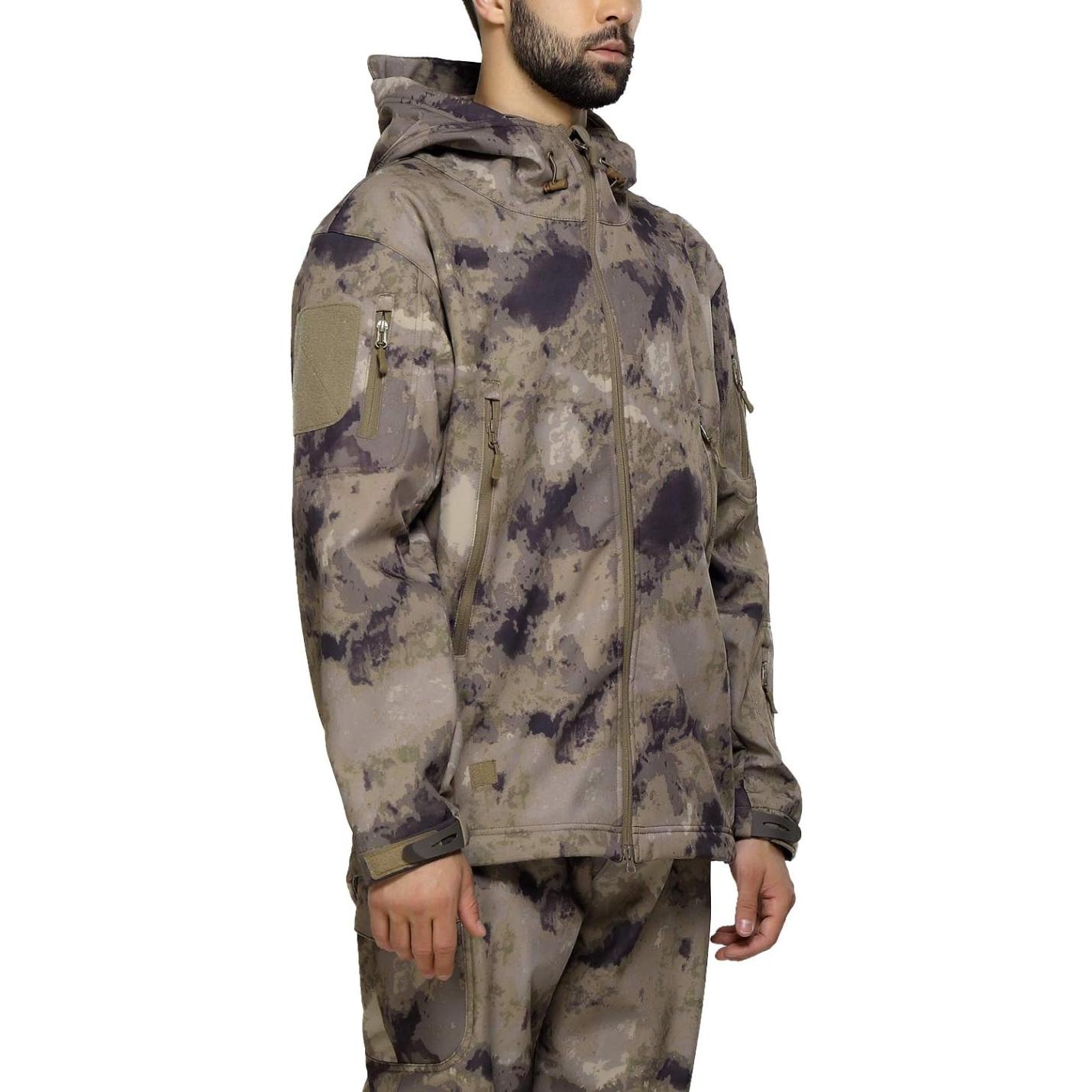 Staande man in zijprofiel, gekleed in een camouflage tactische heren softshell jas en broek met meerdere zakken met ritssluiting.