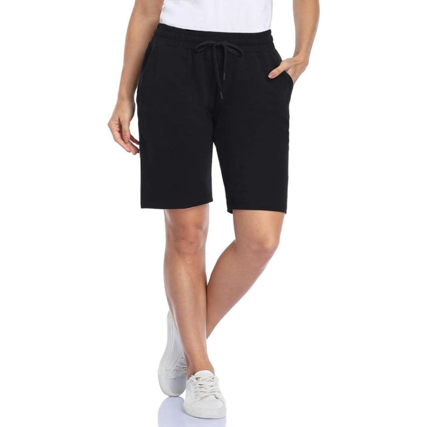 Staande vrouw in Bermudashort voor dames: comfortabel, veelzijdig en perfect voor elke gelegenheid en witte sneakers.