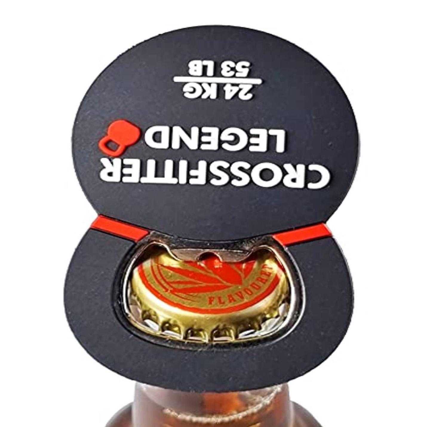 Een zwarte De ultieme combinatie: Bieropener en kettlebell bevestigd aan een flesdop, waarbij de onderkant zichtbaar is met een rood en goud logo, tegen een witte achtergrond.