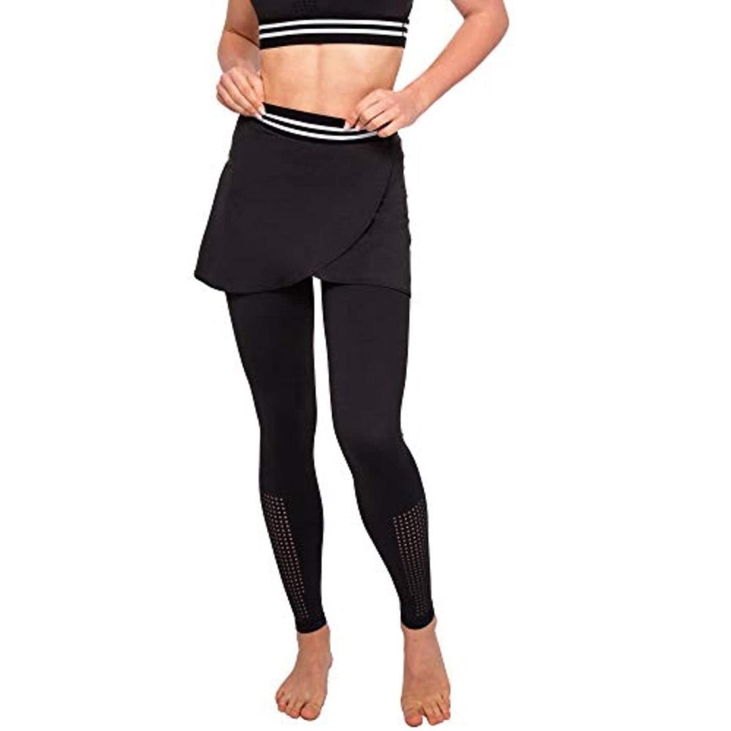 Een vrouw, gekleed in de elegante en comfortabele dameslegging met rok en een crop-top, staat op blote voeten met haar handen op haar heupen.