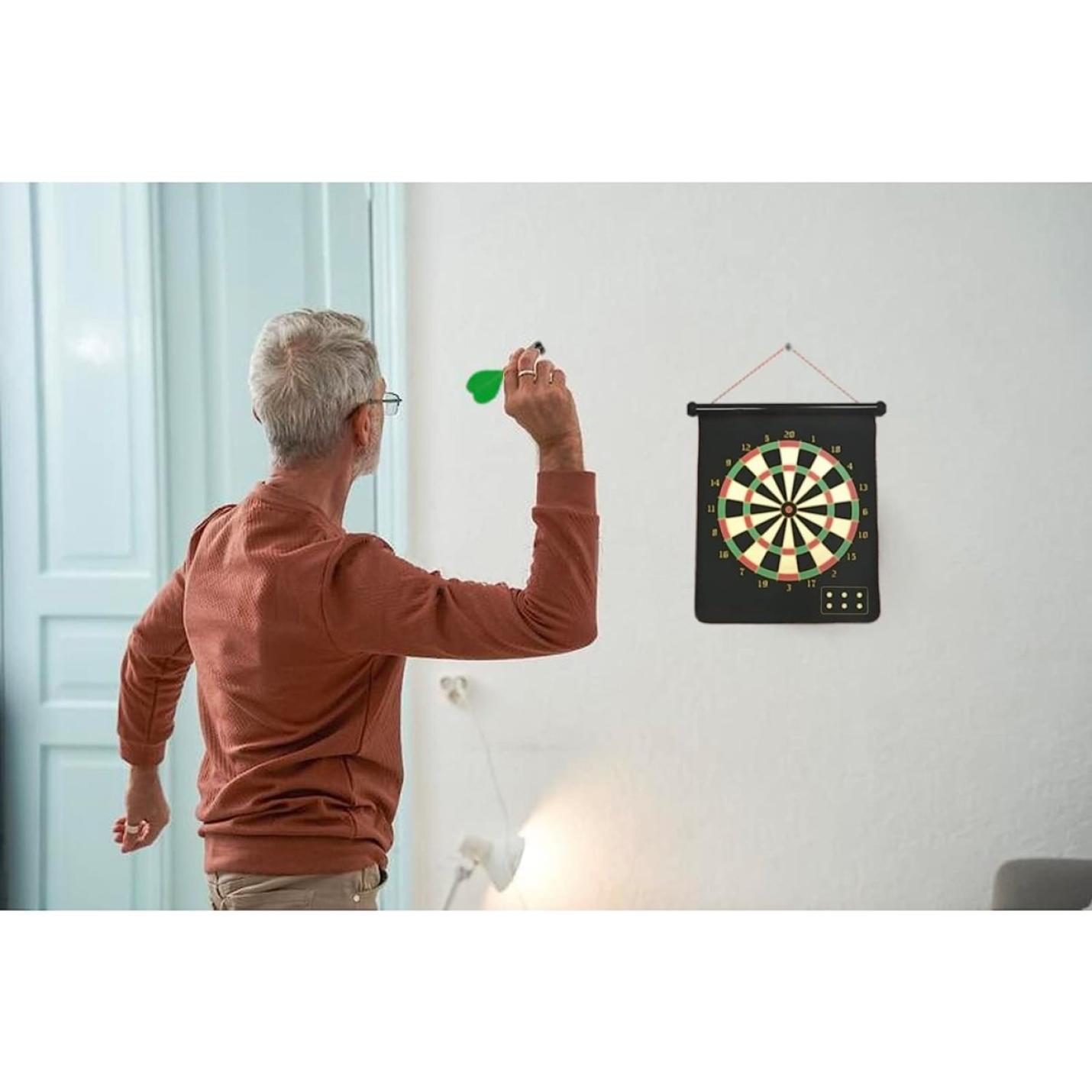 Senior man speelt binnenshuis met een dubbelzijdig magnetisch dartbord.