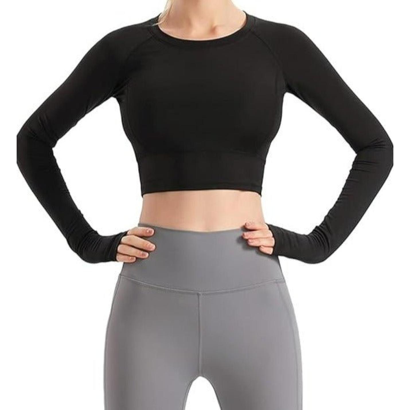 Vrouw, gekleed in een zwarte Naadloze dames fitness crop top en grijze legging met hoge taille, staande met de handen op haar heupen, geïsoleerd op een witte achtergrond.