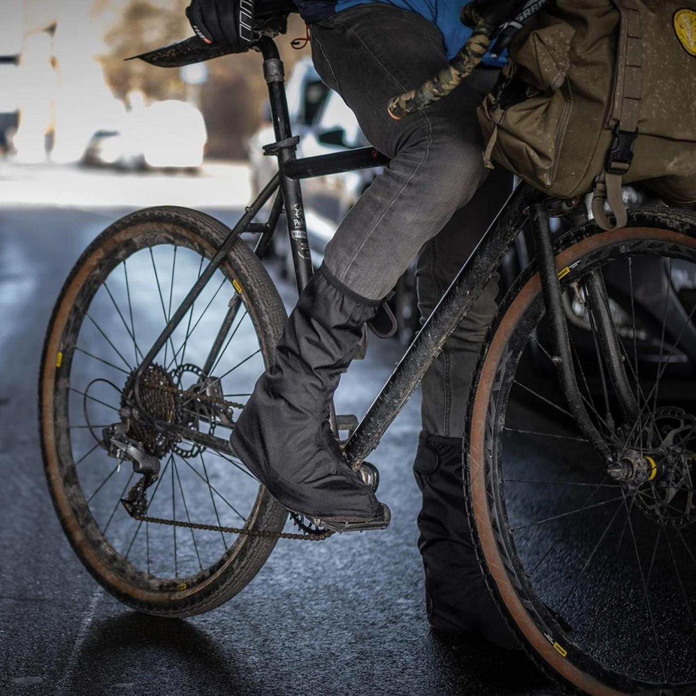 Een fietser die op zijn fiets stapt en zich concentreert op de voet die van de grond afzet, met Regenoverschoenen voor fietsers: blijf droog en stijlvol.