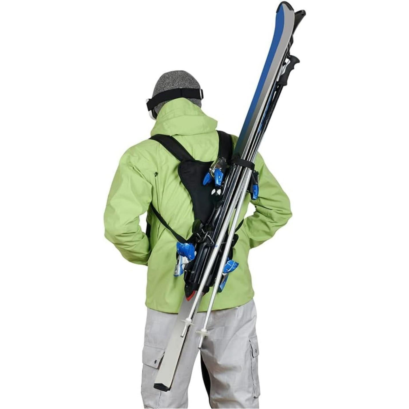 Persoon gekleed in winterkleding en skiback met ski's over zijn schouder.