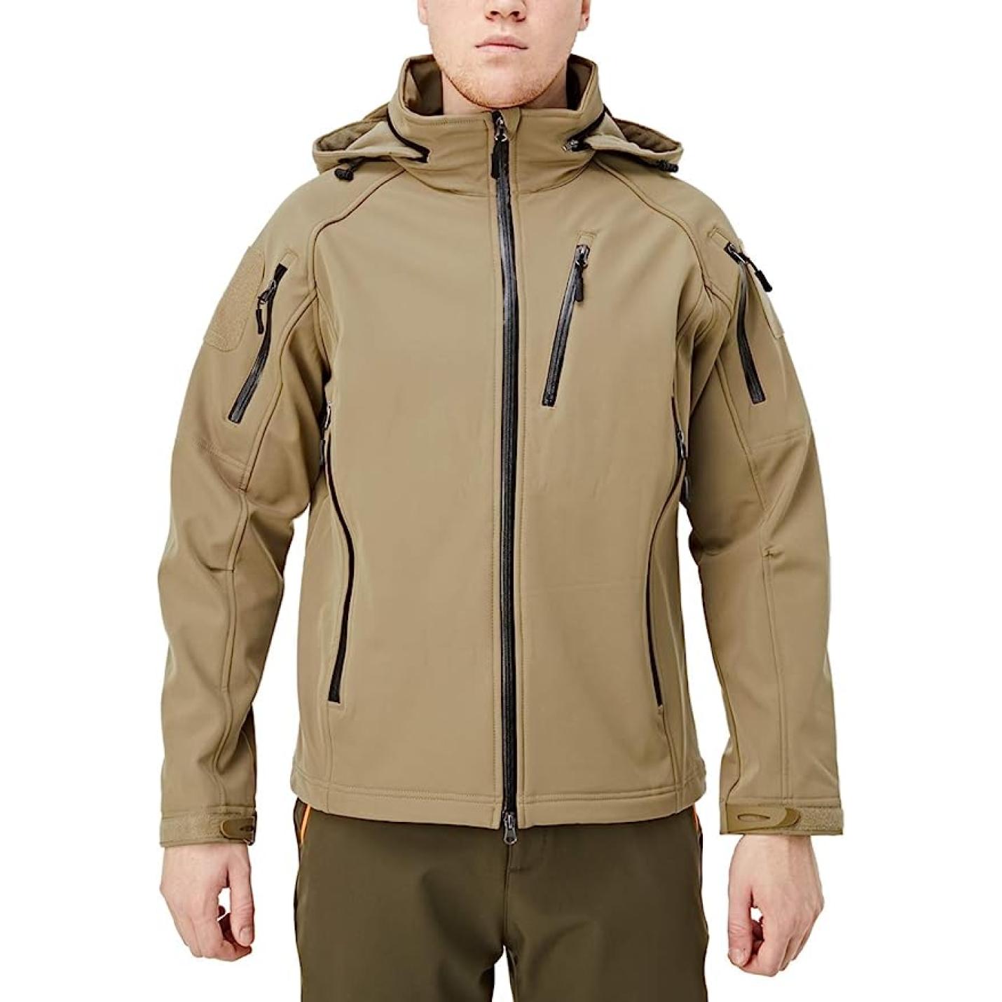 Een man draagt een Blijf warm en droog in elke weersomstandigheid met de waterafstotende softshell jas bij koud weer, duurzame waterafstotende softshell jas met meerdere zakken met ritssluiting en een hoge kraag, staande tegen een effen achtergrond.