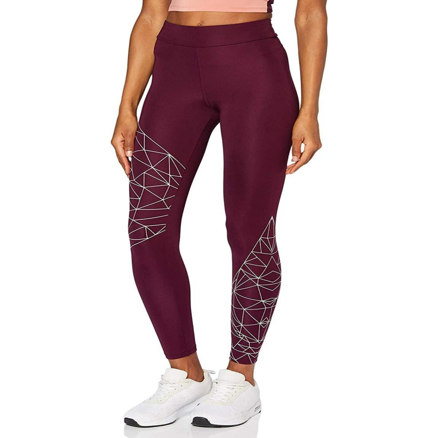 Een vrouw die Ervaar comfort en stijl met onze sportlegging voor dames draagt met een wit geometrisch patroon op één been, gecombineerd met witte sneakers.