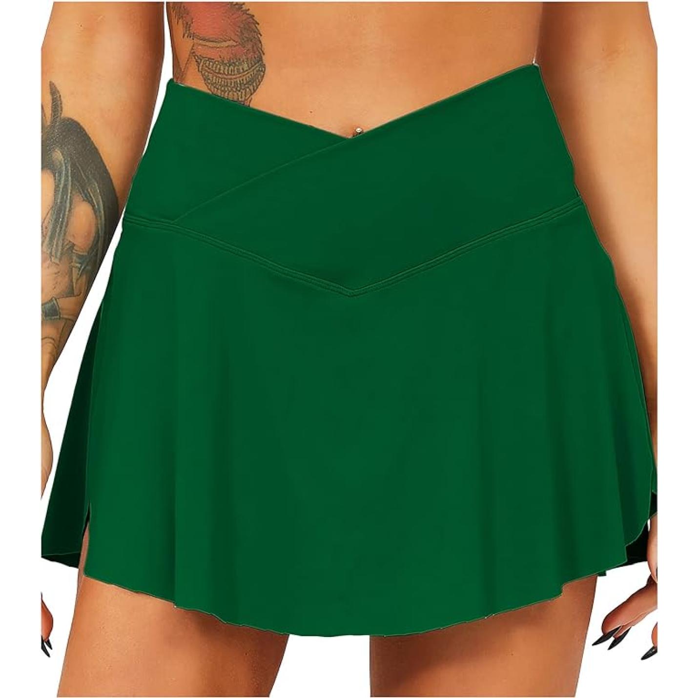 Close-up van een groene tennisrok met broek van een vrouw met een zichtbare tatoeage op haar bovenarm.