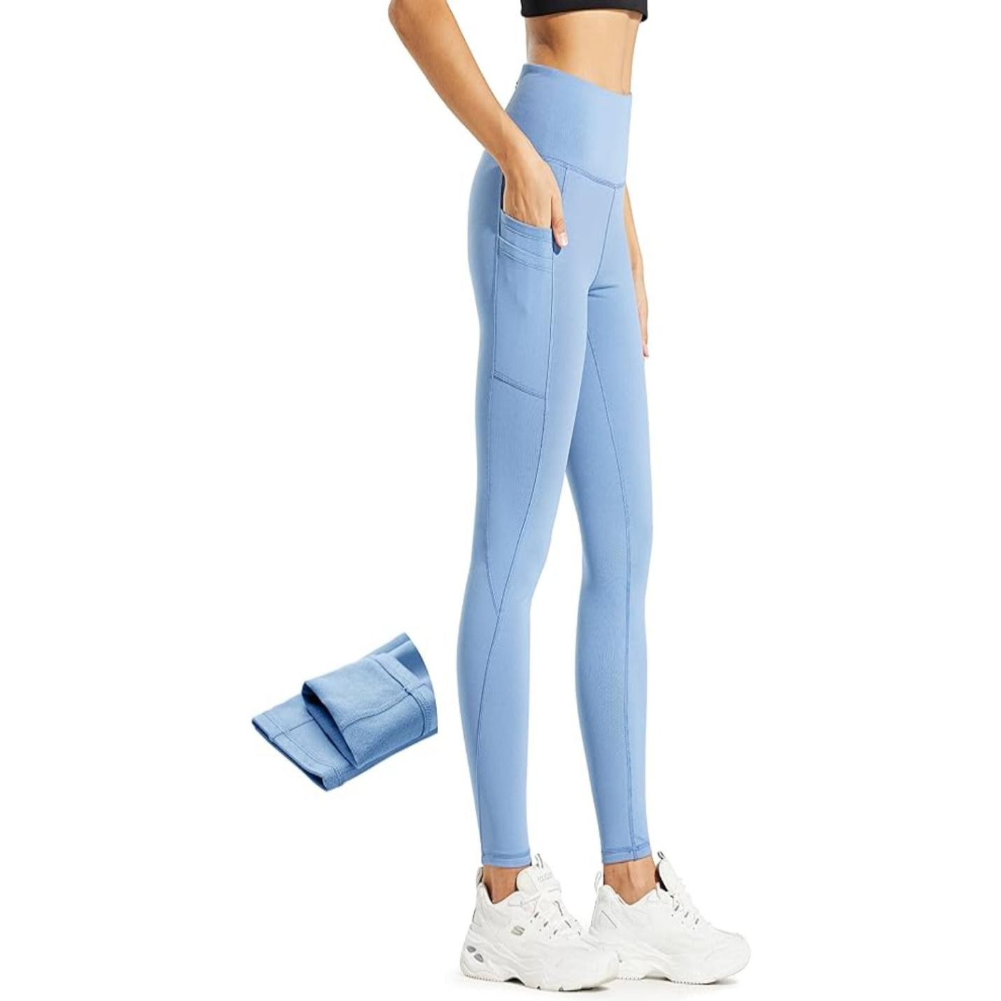 Vrouw toont Warm, comfortabel en waterafstotend: de perfecte thermische legging voor dames in het blauw met zakken, gecombineerd met witte sneakers.