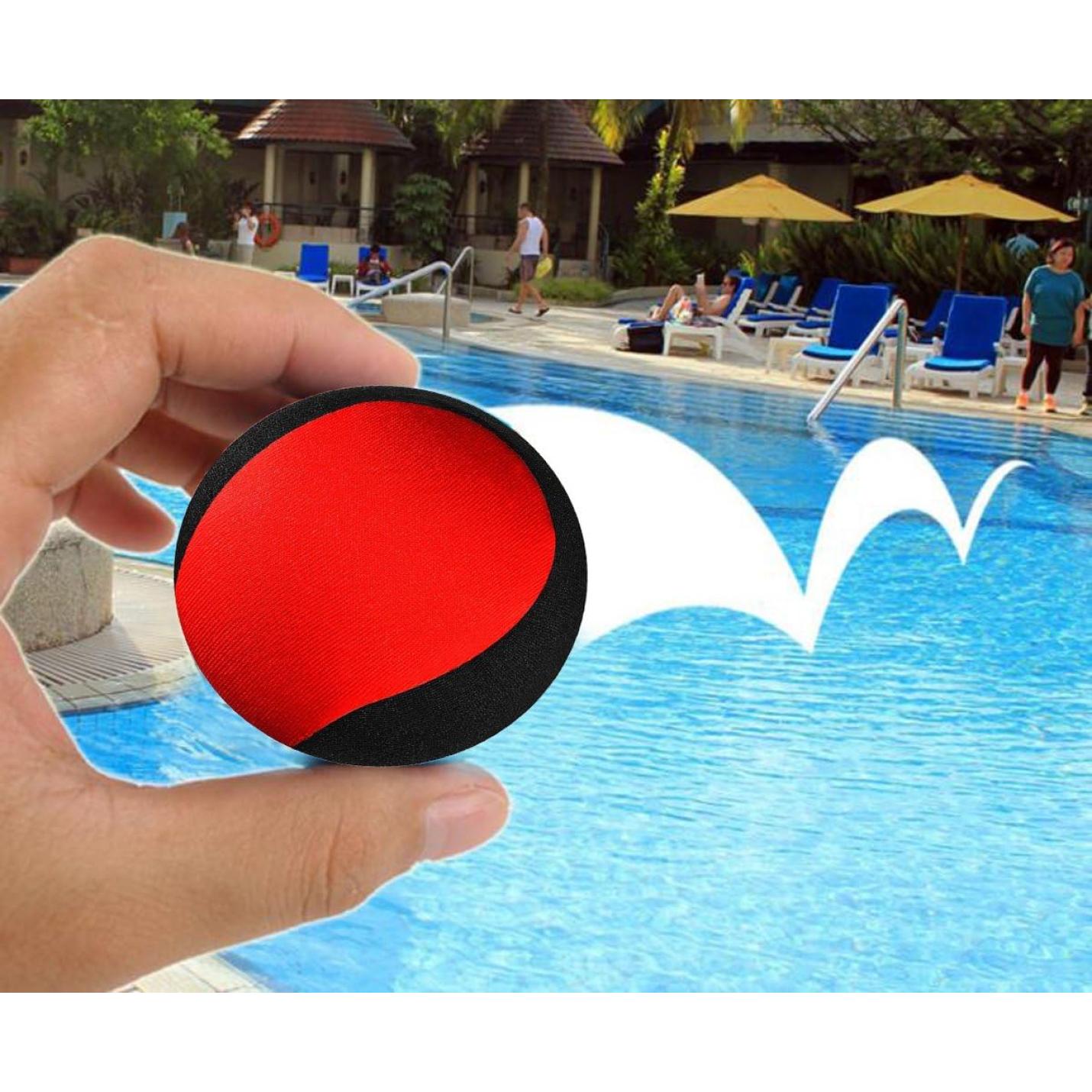 Hand met een Waterballen: een waterpret voor het hele gezin, die een deel van een levendig tafereel bij een zwembad beslaat met loungende mensen en een hotel op de achtergrond.